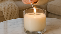 Person lighting a candle on a marble table with a cozy living room background