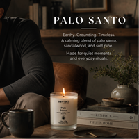 Man sitting with a Palo Santo candle and mug in a cozy room setting