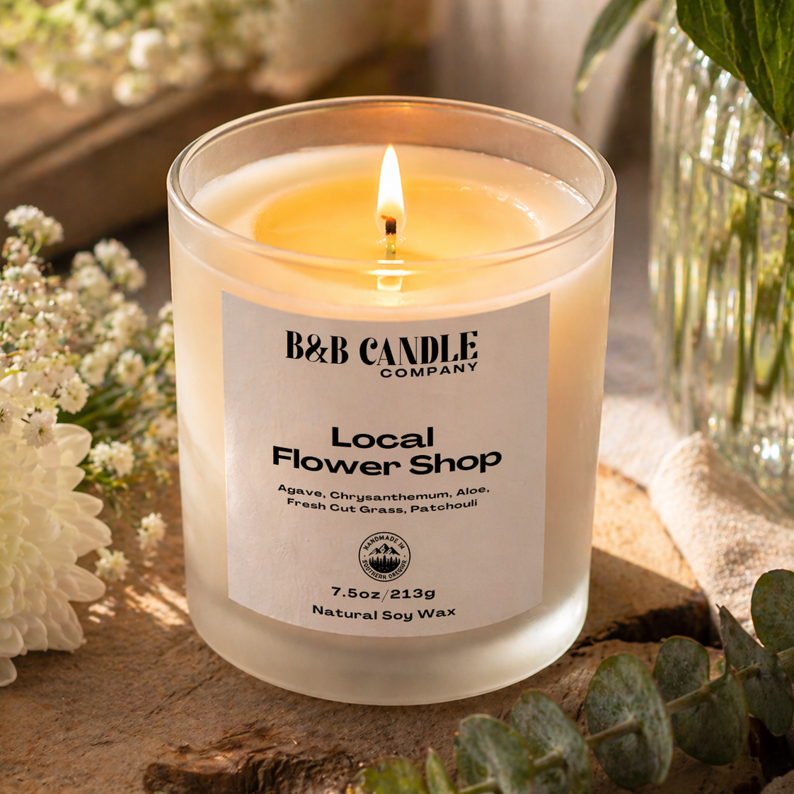 B&B Candle Company candle with flowers and greenery in the background