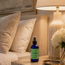Blue bottle with green label on a nightstand next to a lamp and decorative items.